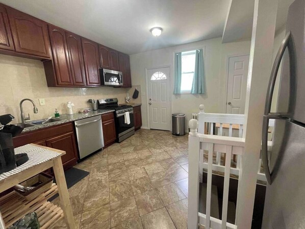 A kitchen with wooden cabinets, stainless steel appliances, a tiled floor, and a white refrigerator.