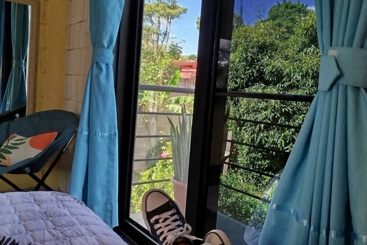 A room with a bed, a chair, and a window with curtains.
