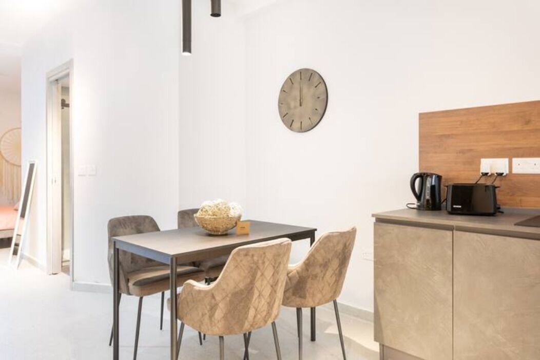 Une cuisine moderne avec un plan de travail en bois, une machine à café intégrée et une horloge murale.