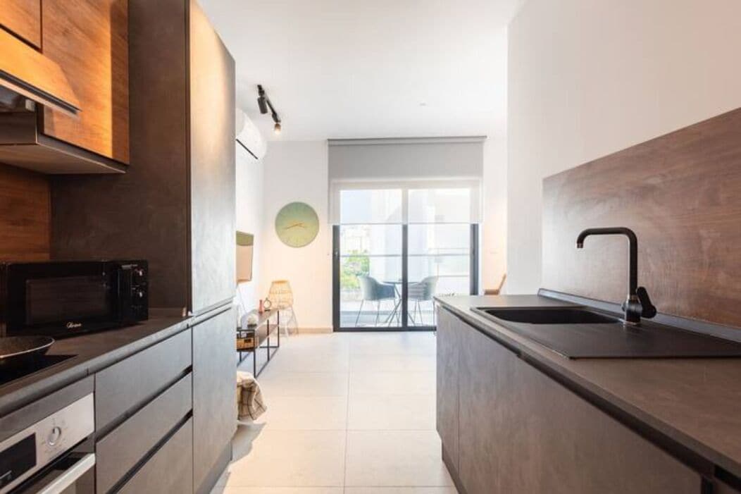 Una cocina moderna con una isla central, horno empotrado y microondas.