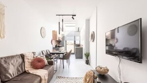 Ein modernes Wohnzimmer mit Sofa, Fernseher und Essbereich.