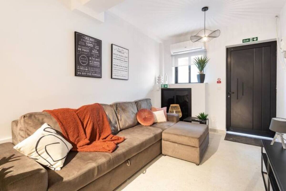 A modern living room with a sectional sofa, a fireplace, and a door with an exit sign.