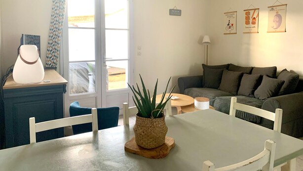 A living room with a sofa, a dining table with chairs, a lamp, and a hanging light fixture. - AURORE (30 chemin des Burons, n°15, Le Bois Plage) (Le Bois-Plage-en-Ré)