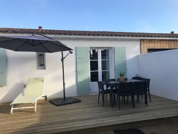 A patio with a table and chairs, a single chair, and an umbrella.
