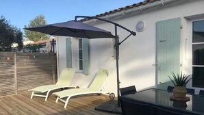 A patio with two sun loungers, a table, and a large umbrella. - AURORE (30 chemin des Burons, n°15, Le Bois Plage) (Le Bois-Plage-en-Ré)