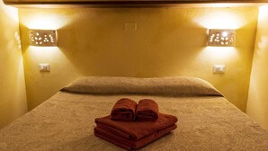 A hotel room with a bed, two wall sconces, and a folded towel on the bed. - Elegant deluxe cottage close to beaches (Sardegna)