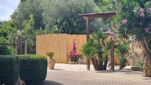 A garden with a pergola, potted plants, and a stone wall. - Elegant deluxe cottage close to beaches (Sardegna)