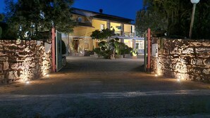 A stone gate leading to a building with a balcony, surrounded by greenery. - Elegant deluxe cottage close to beaches (Sardegna)