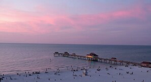 A beach with a pier extending into the sea, featuring several covered structures.