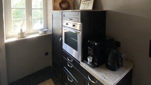 Eine kleine Küche mit Backofen, Kaffeemaschine und einem Hirschgeweih an der Wand.