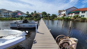 A wooden dock extending into calm water with boats moored at the end.