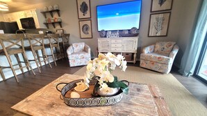 A living room with a wooden coffee table, chairs, a TV, and decorative wall art.