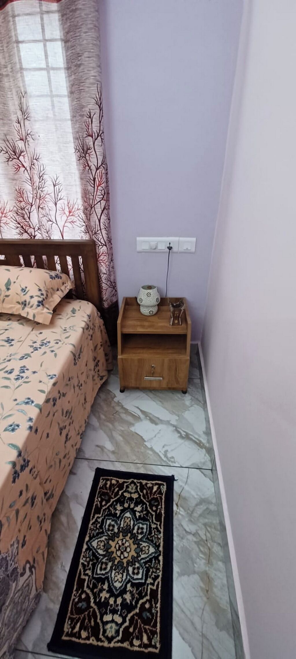 Un dormitorio con cama, mesita de noche y alfombra.