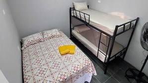 A small, compact room with a single bed and a bunk bed, a standing fan, and tiled flooring. - Hostel Vila Brás  (São Paulo)