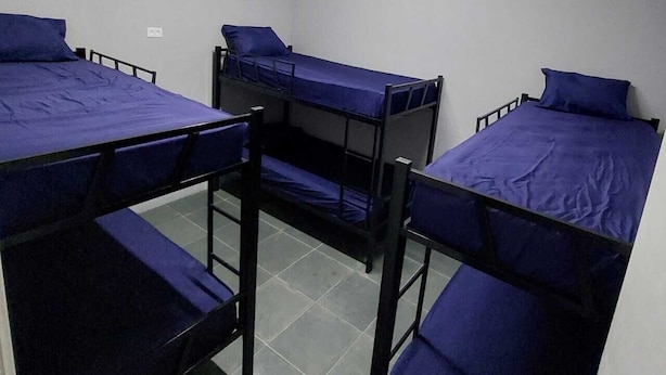 A dormitory room with three bunk beds, each with a blue mattress and pillow. - Hostel Vila Brás  (São Paulo)