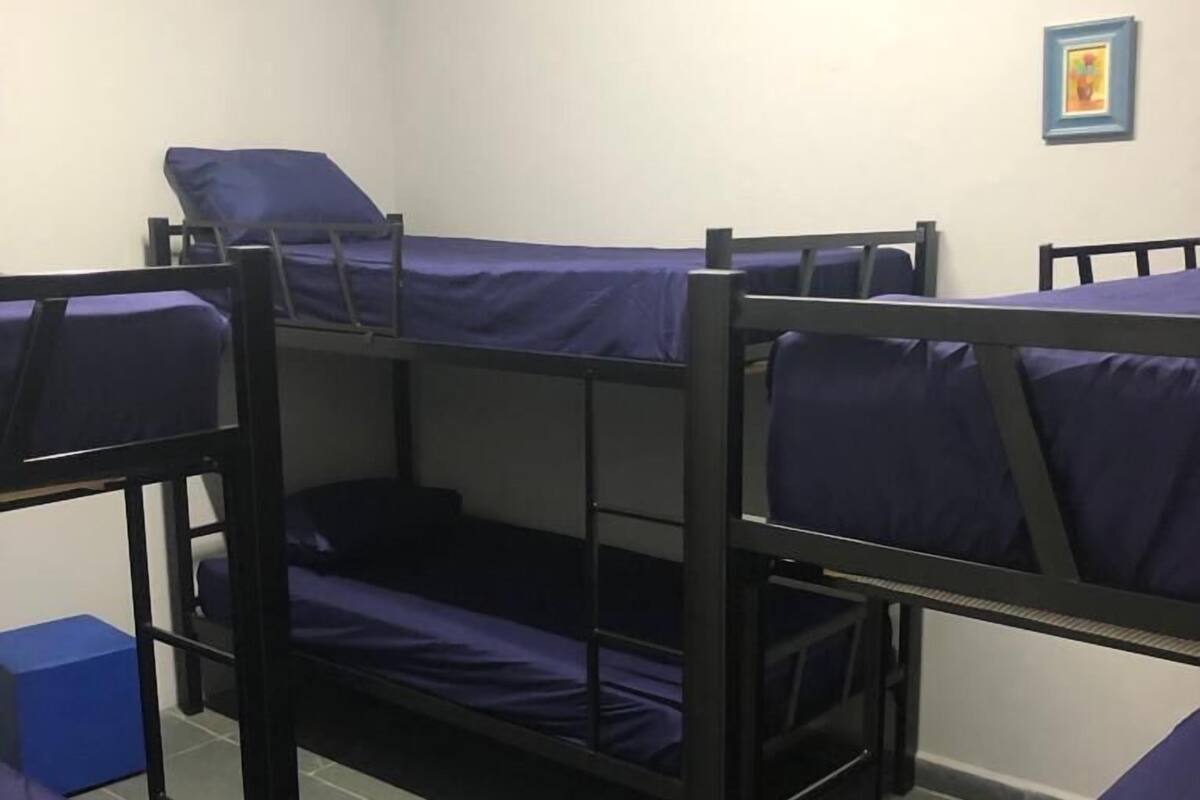 A dormitory room with bunk beds and a small blue box on the floor.