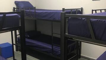 Ein Schlafsaalzimmer mit Etagenbetten und einer kleinen blauen Kiste auf dem Boden.