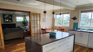 A modern kitchen with a central island, wooden flooring, and pendant lighting. - # 40 At the Beach (Waitārere Beach)