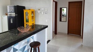Una cocina con un refrigerador negro, un armario amarillo y una encimera negra.