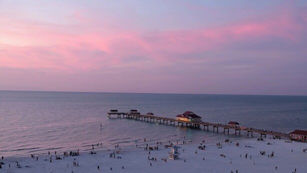 A beach with a pier extending into the sea, featuring several covered structures.