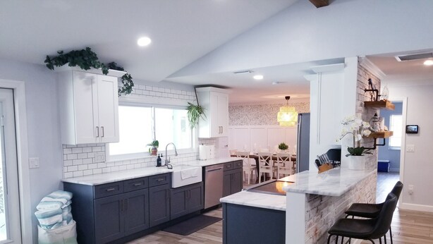 A modern kitchen with white cabinets, a marble island, and a dining area with a wooden table and chairs.