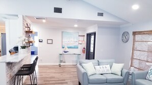 A modern living room with a sofa, a coffee table, and a kitchen area with a bar.