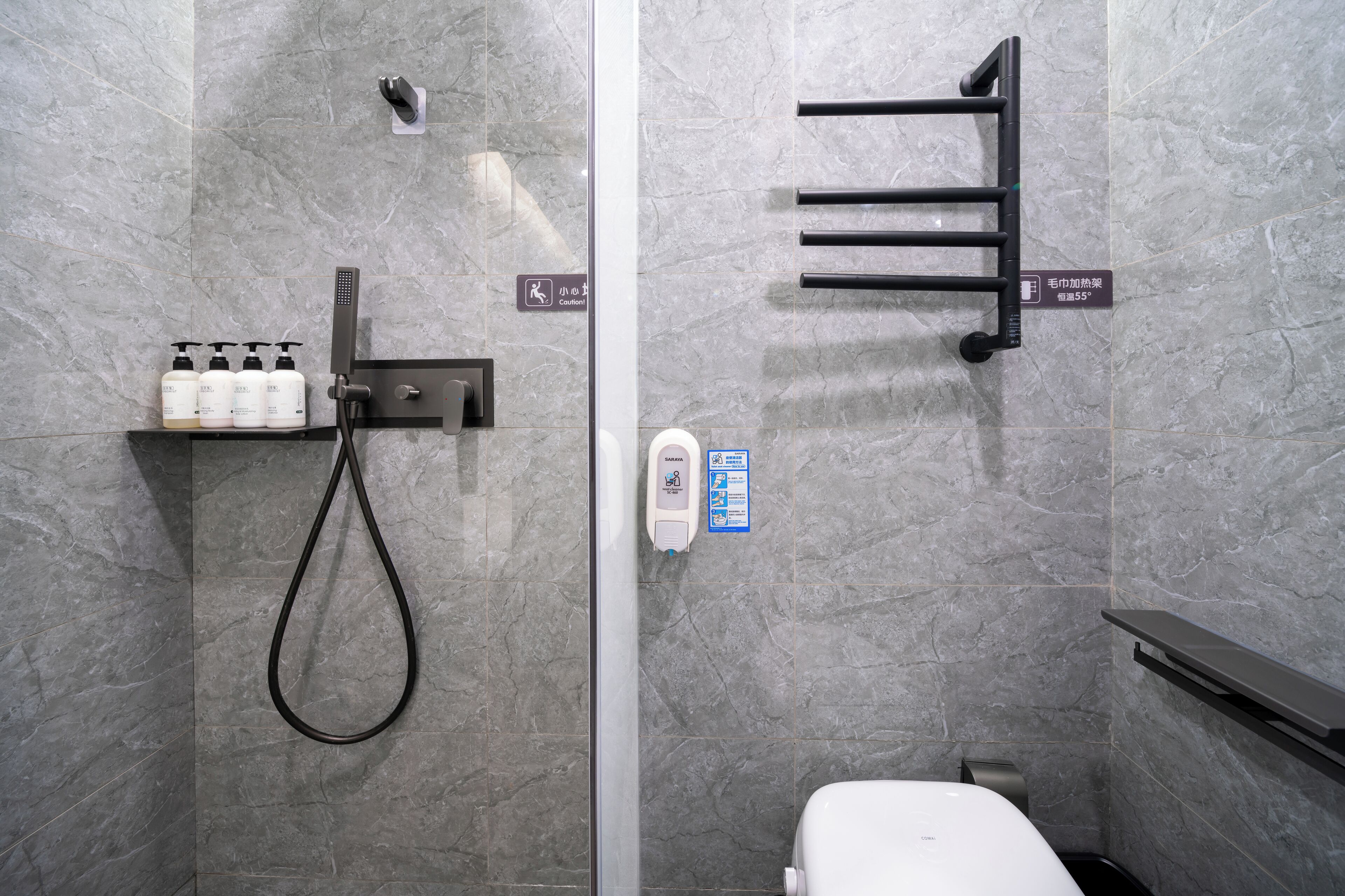 A modern bathroom with a shower, toilet, and hand sanitizer dispenser.