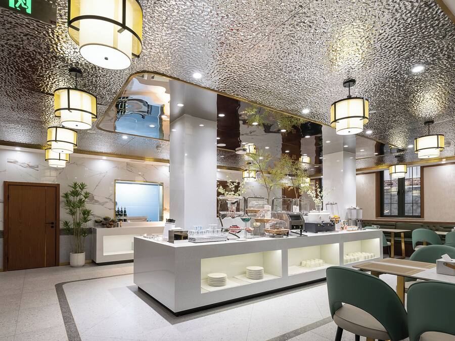 A modern cafe with a central counter, seating area, and decorative ceiling.