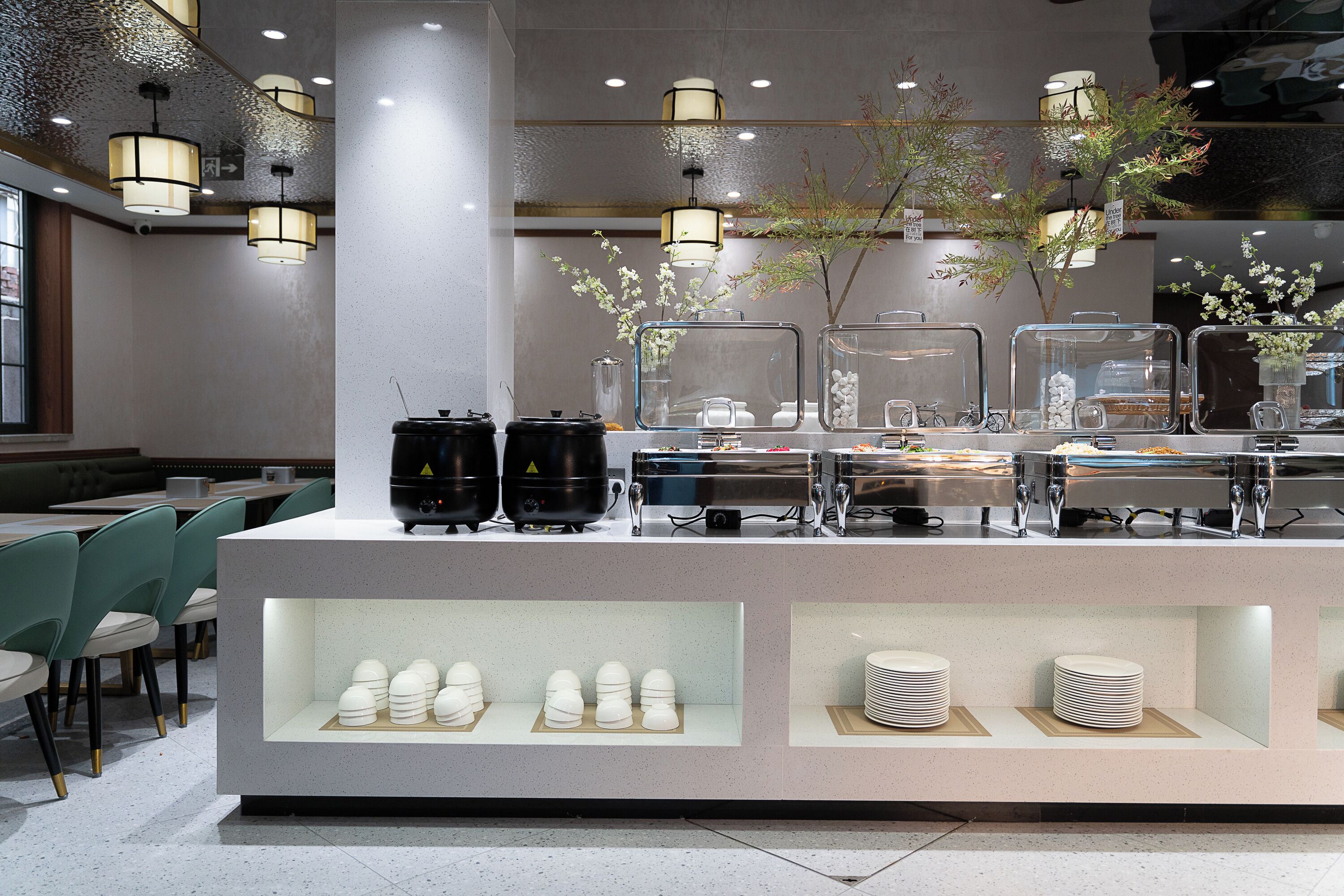 A modern cafe with a counter displaying food items and a seating area with green chairs.