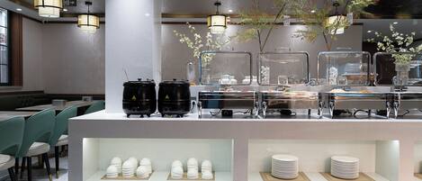 A modern cafe with a counter displaying food items and a seating area with green chairs.
