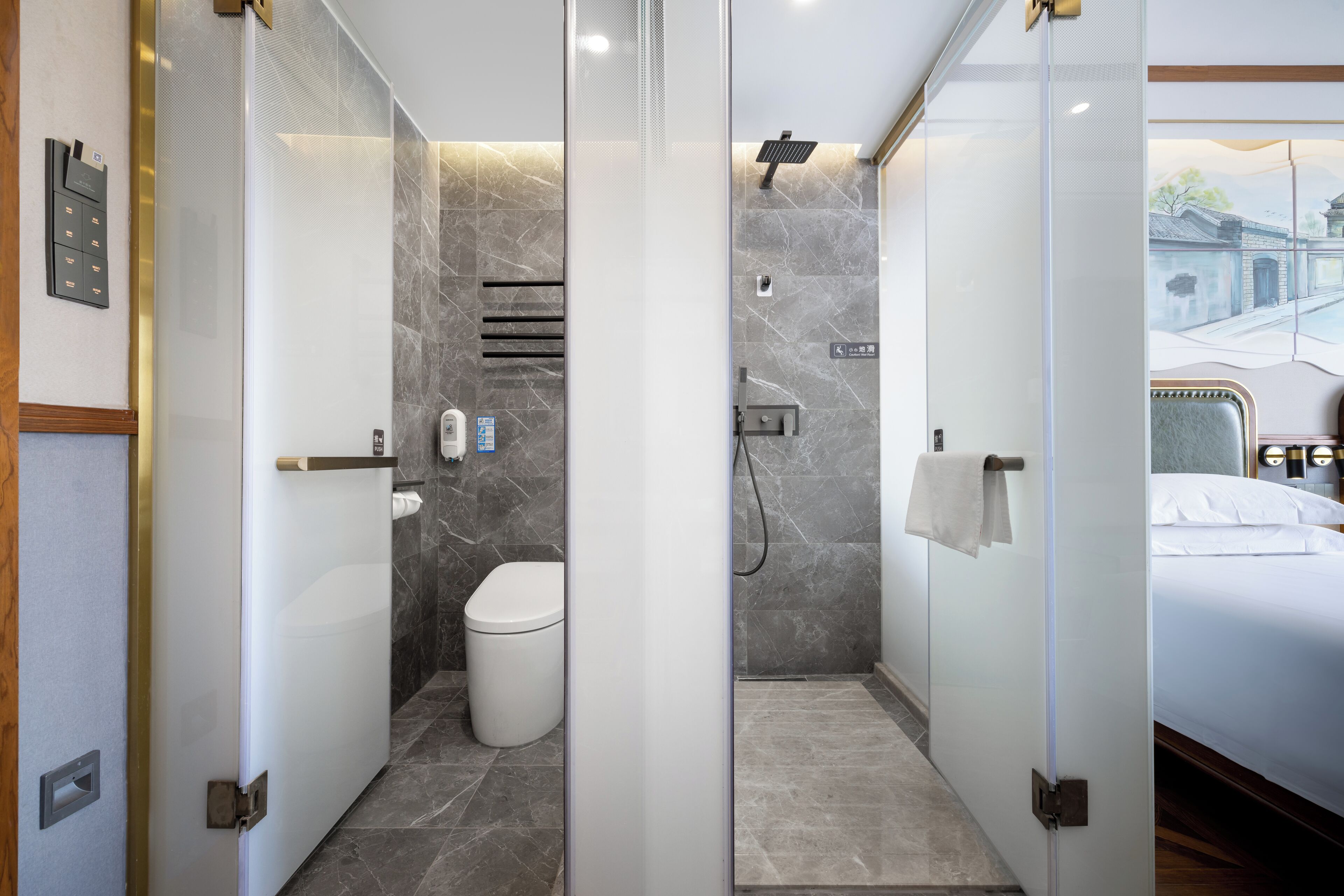 A modern bathroom with a toilet, shower, and glass partition.