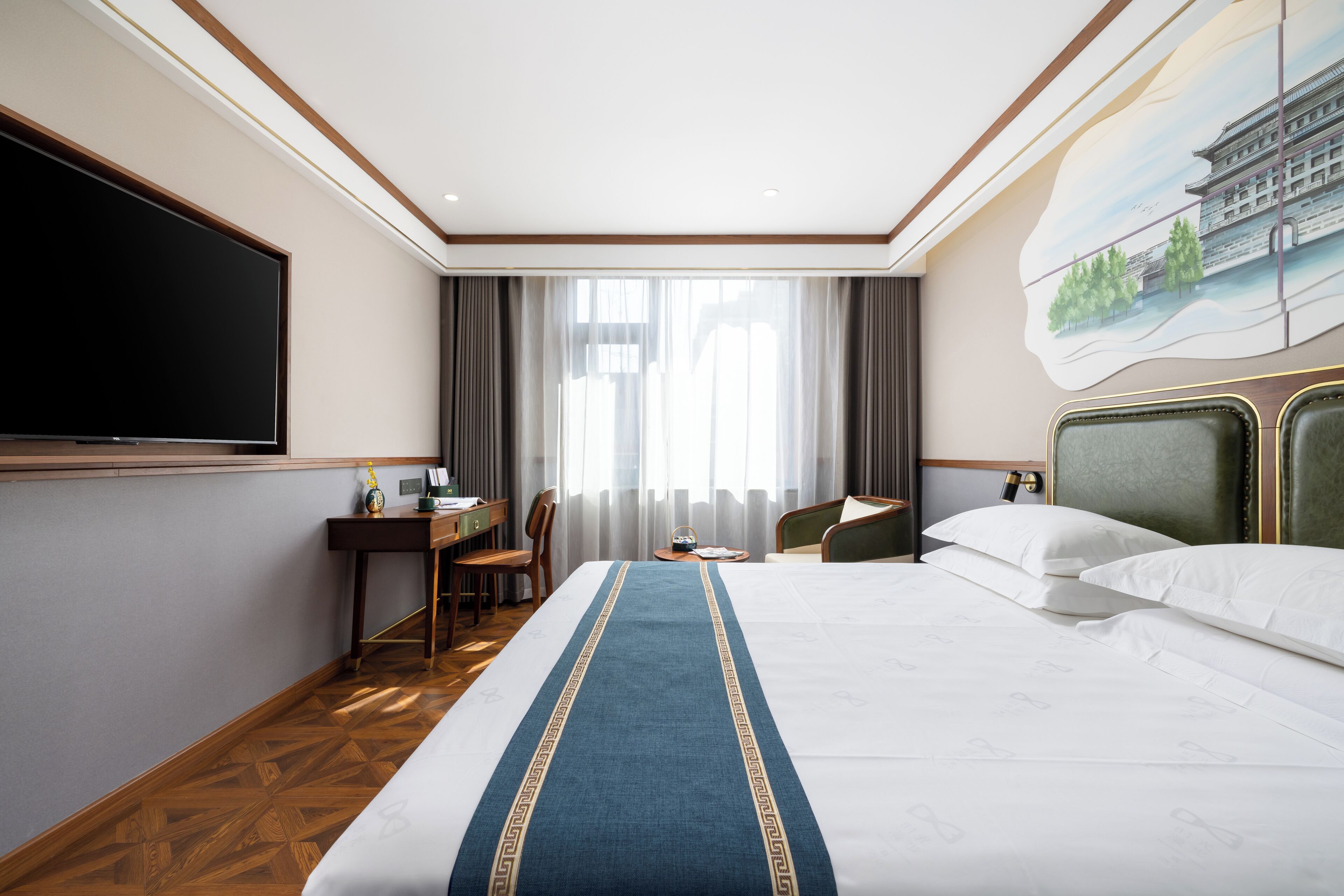 A hotel room with a large bed, a desk with a chair, a television, and a painting on the wall.