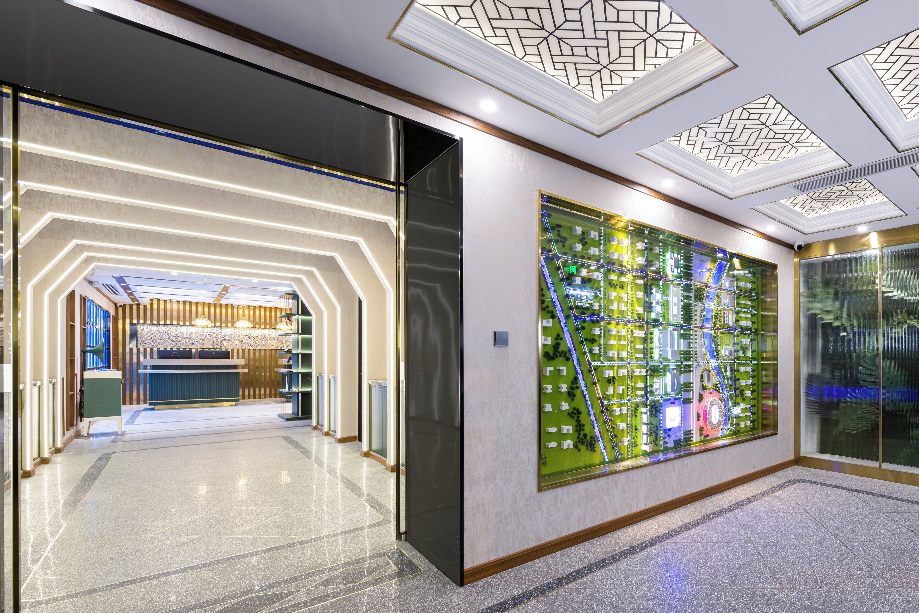 A modern hotel lobby with a geometric patterned ceiling, a reception desk, and a large decorative wall with a circuit board design.