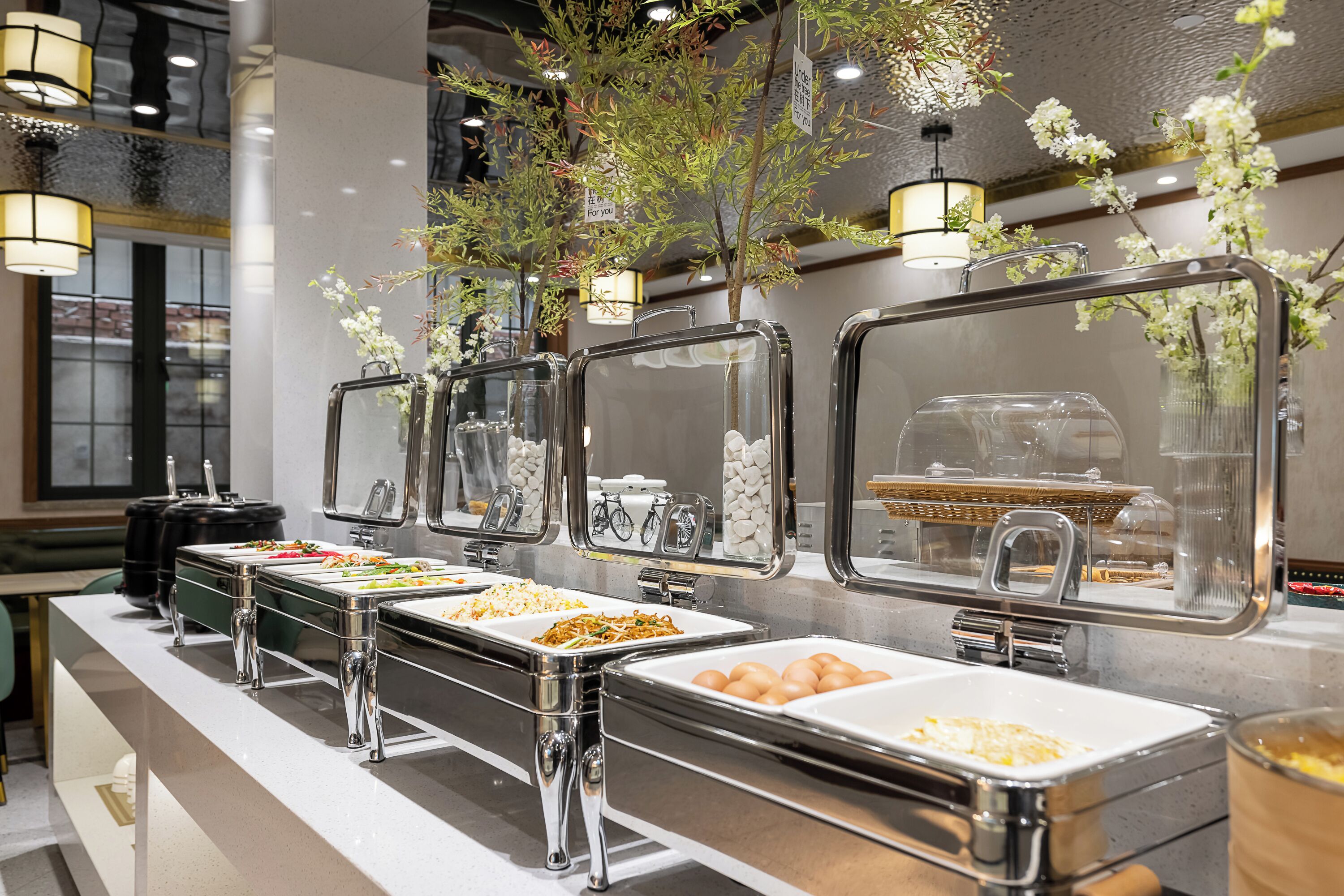 A buffet setup with multiple food stations, each with a glass cover and metal frame.