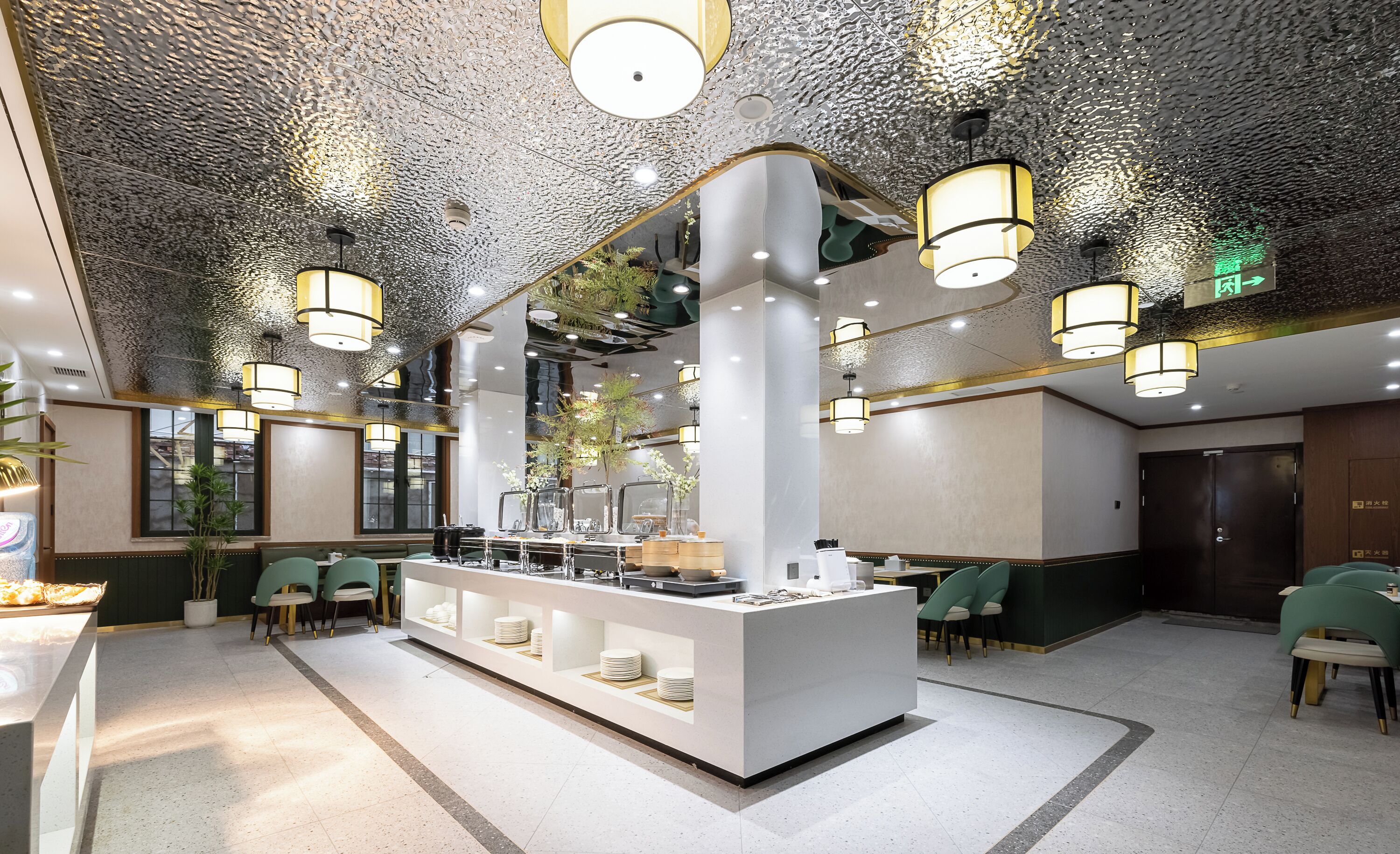 Un hall d’hôtel moderne avec un comptoir central, des chaises vertes et un plafond à la texture originale.