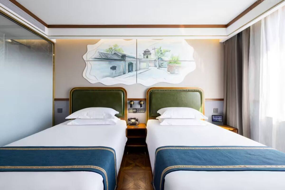 A hotel room with two beds, a large wall art piece, a telephone, and a nightstand.