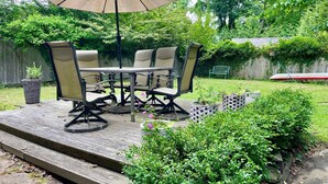 Eine Terrasse mit Tisch und Stühlen, einem großen Sonnenschirm und einem Holzdeck.