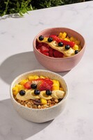 Deux saladiers de salade de fruits sur une table en marbre.