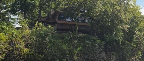 A river with a wooden bridge and a building on the opposite bank.