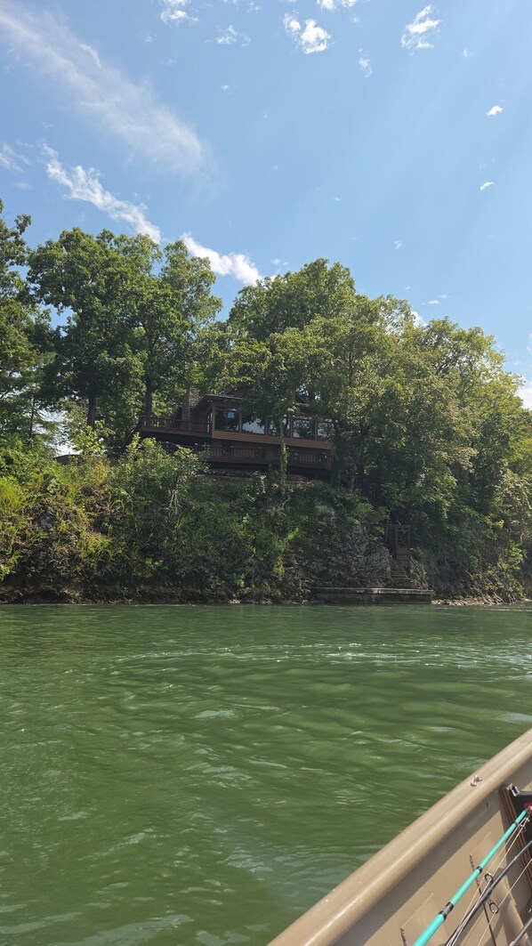 A river with a wooden bridge and a building on the opposite bank.