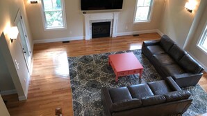 Uma sala de estar com lareira, uma grande TV de tela plana e um sofá seccional.