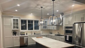 Uma cozinha moderna com armários brancos, eletrodomésticos de aço inoxidável e uma ilha grande.