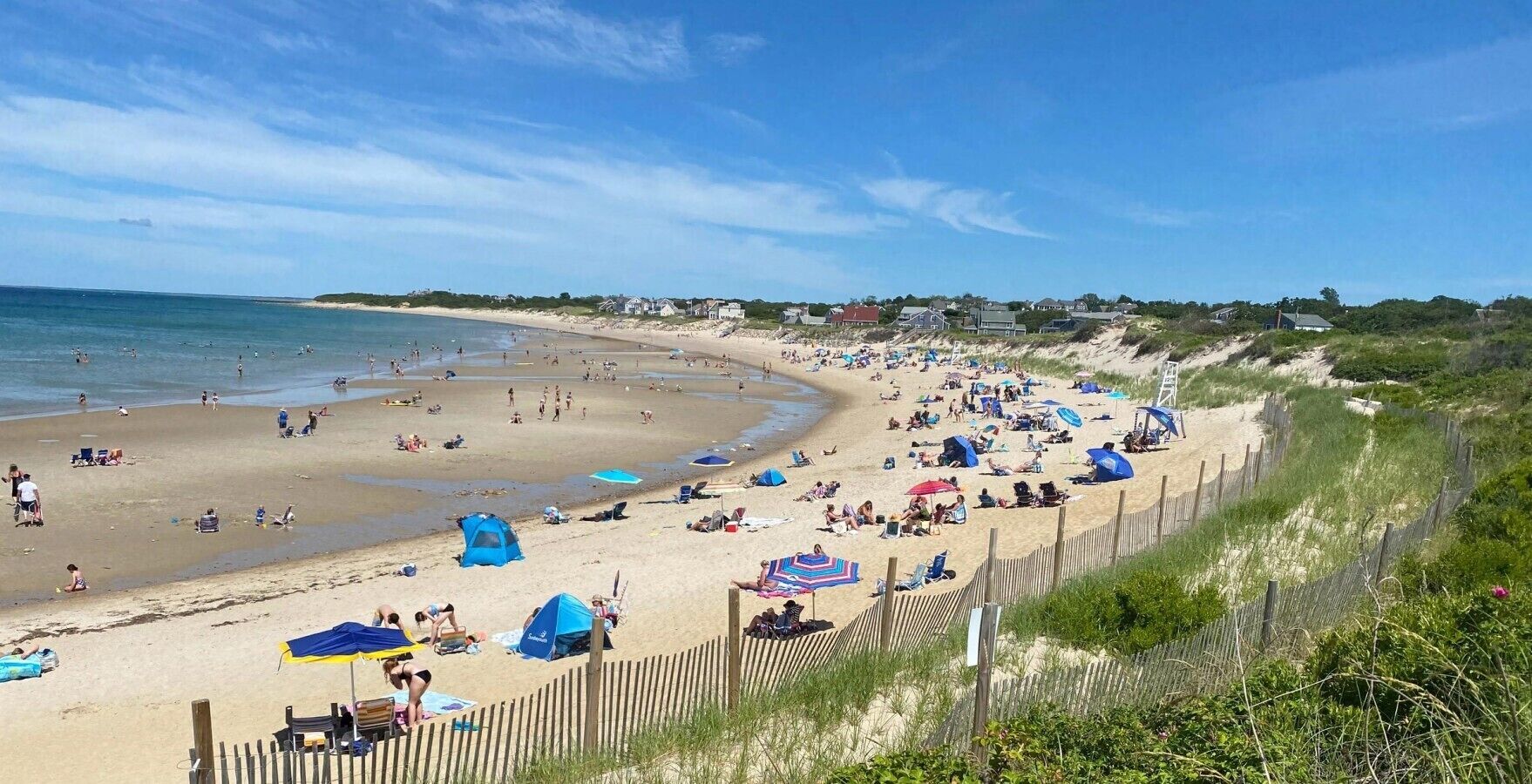 A beach with people, tents, and umbrellas.