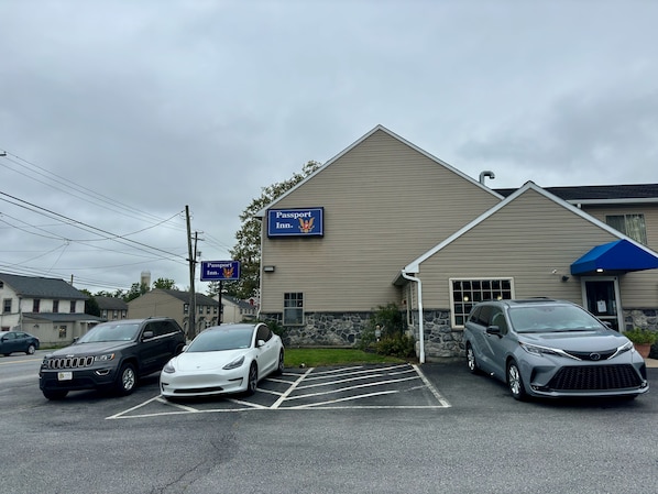 A building with a sign reading "Passport Inn" and a parking lot with three cars.