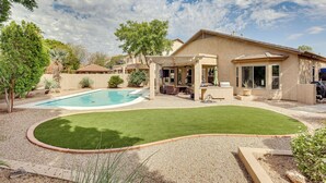 Ein Garten mit Swimmingpool, Terrasse und Rasenfläche.