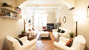 A living room with two white sofas, a coffee table, a TV, and bookshelves. - Casa Clara Luxury with Terrace (Lucca)