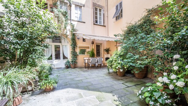 A courtyard with potted plants, a bench, and a door leading to a building. - Casa Clara Luxury with Terrace (Lucca)
