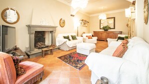 A living room with a fireplace, white sofas, a red rug, and a television. - Casa Clara Luxury with Terrace (Lucca)