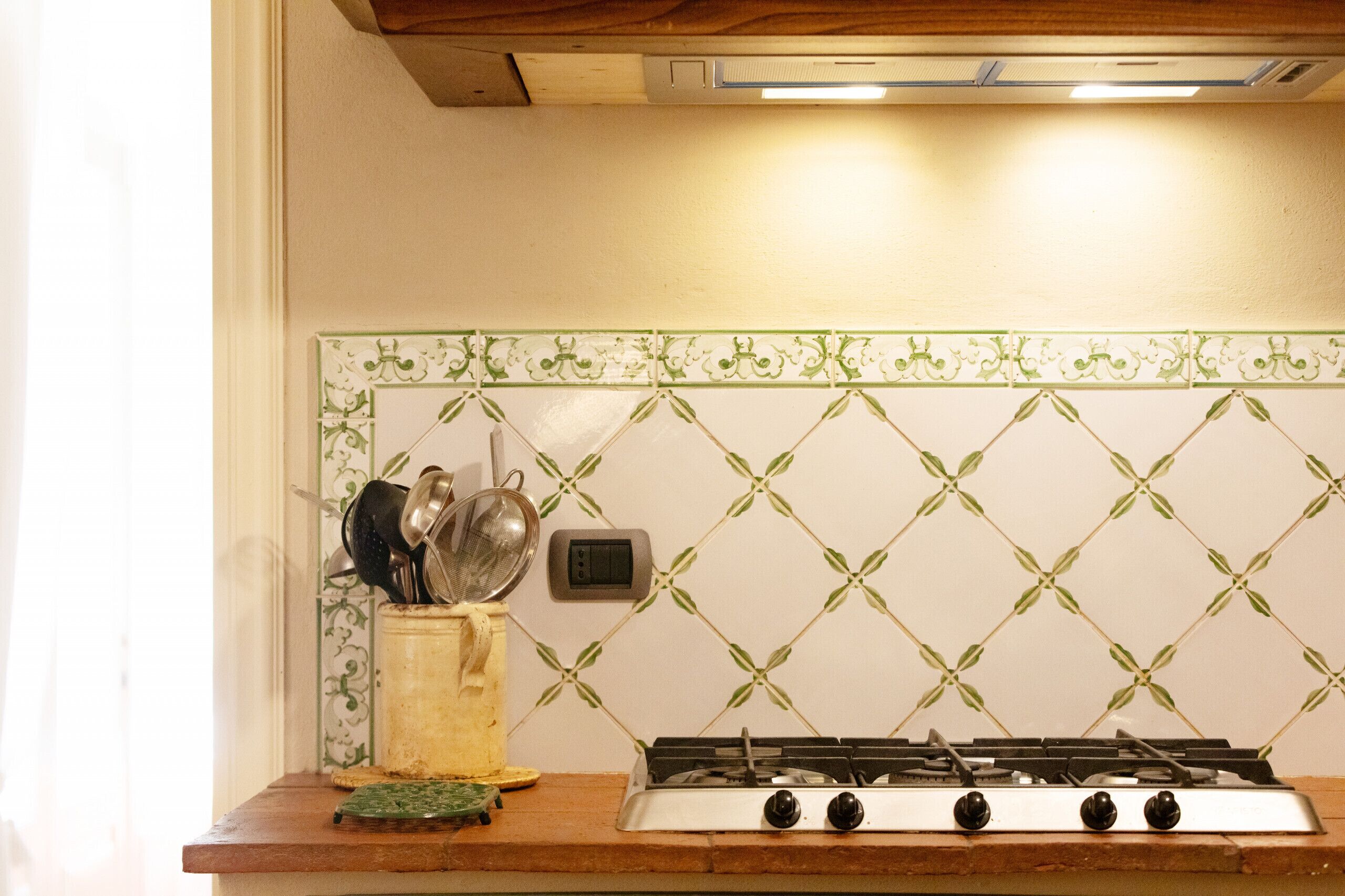 A kitchen with a gas stove, a wall-mounted electrical outlet, and a tiled backsplash.