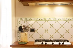 Uma cozinha com fogão a gás, tomada elétrica na parede e painel de azulejos.